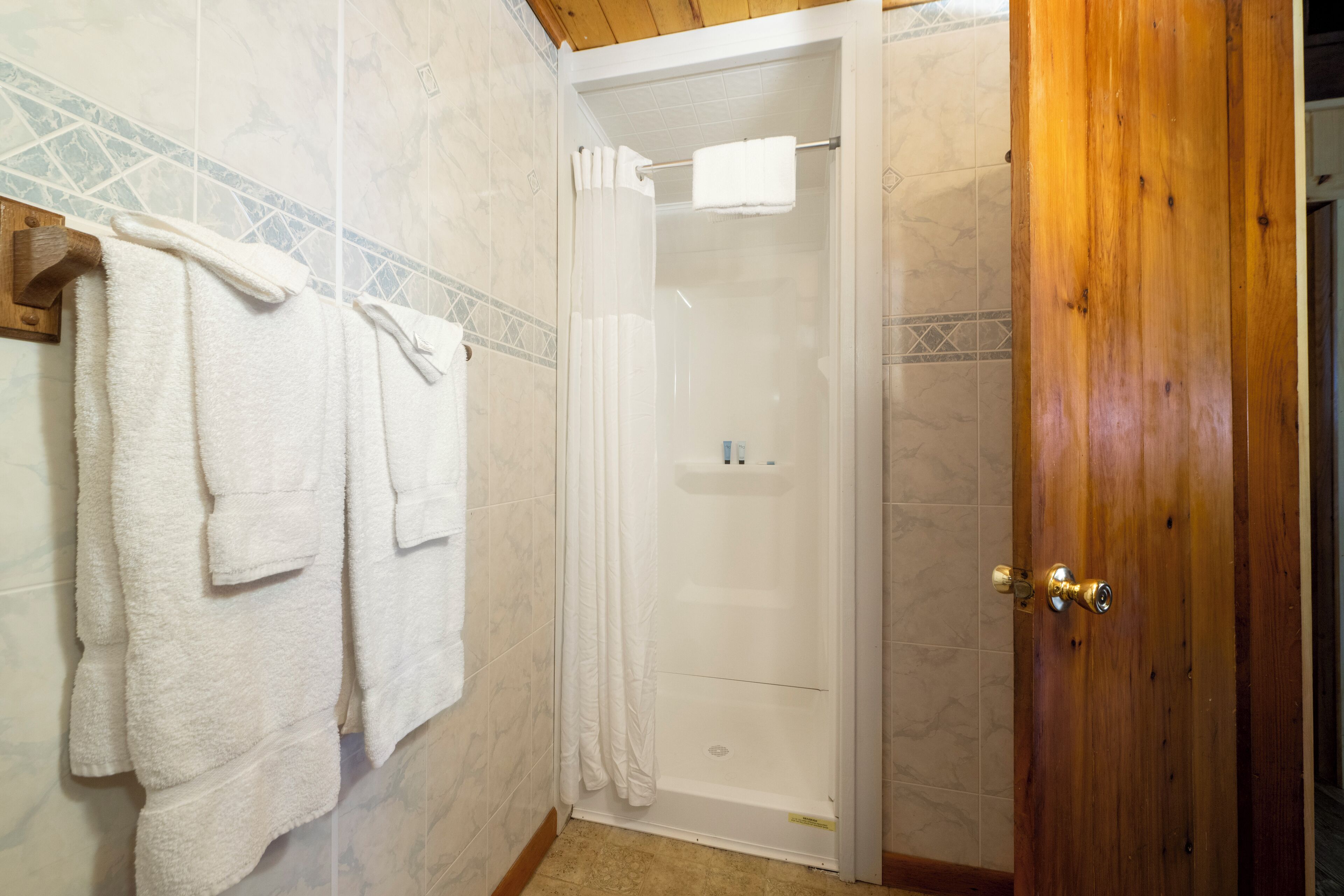 A bathroom with a shower, tiled walls, and a wooden door.