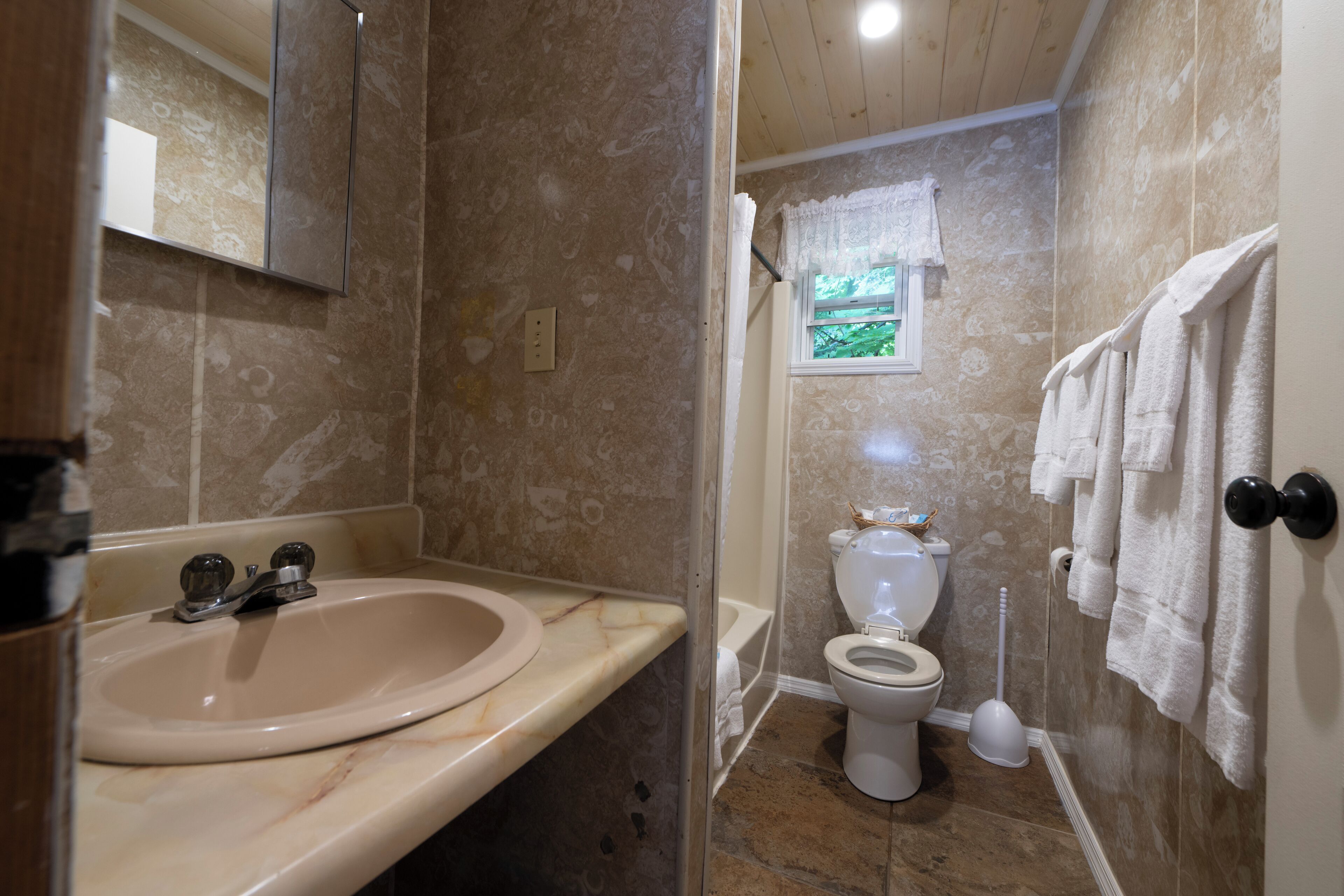 A bathroom with a marble sink, a toilet, and a shower area.