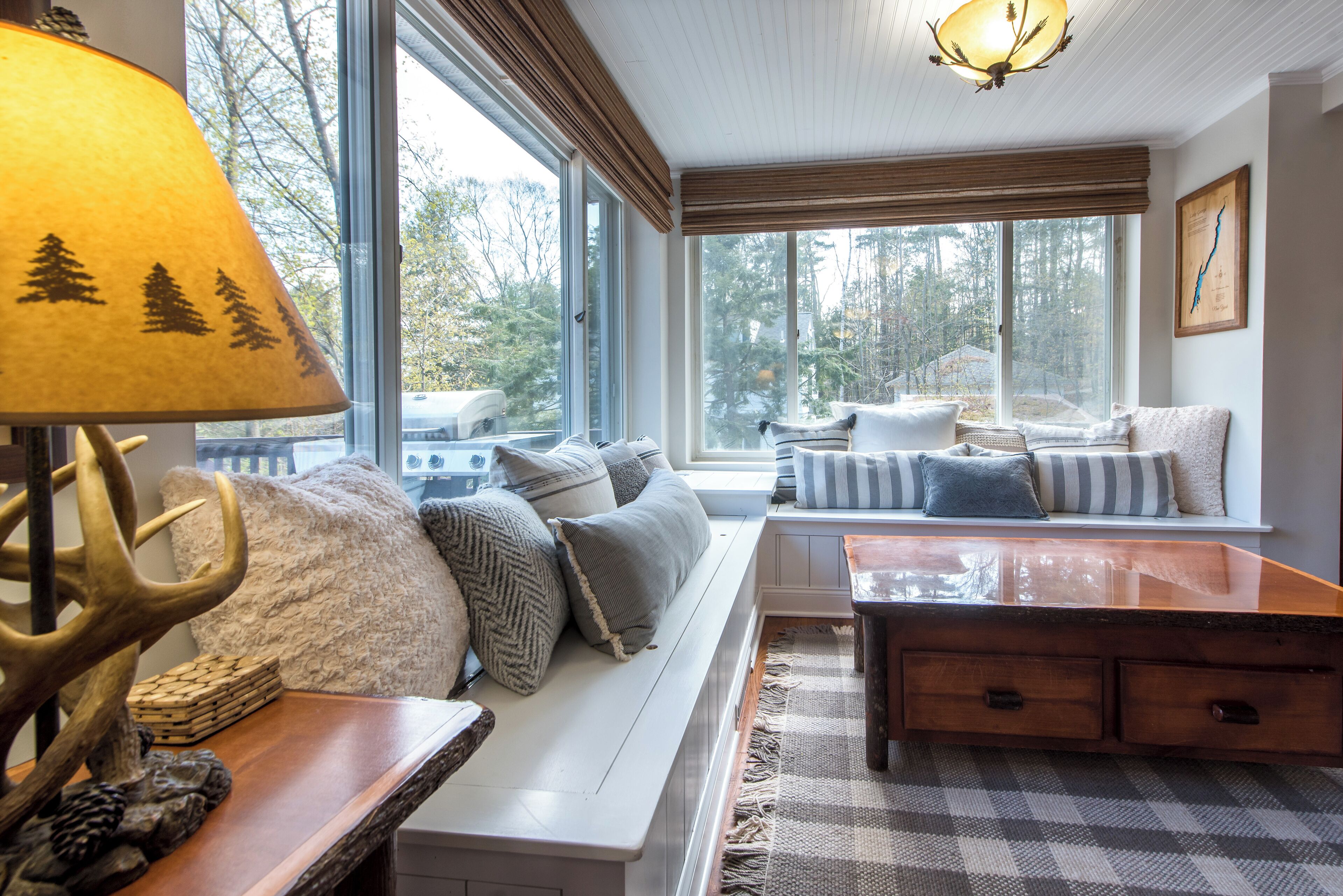 Una habitación acogedora con un banco, una mesa y una lámpara con motivos de árboles.