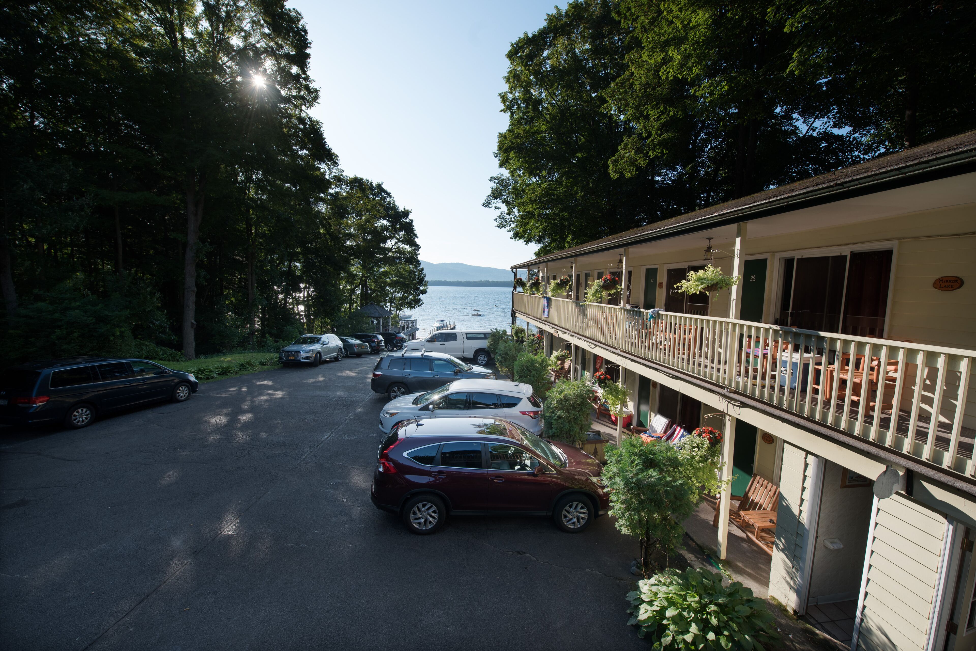 A motel with a parking lot, a balcony with outdoor seating, and a view of the lake.