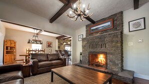 A living room with a stone fireplace, leather furniture, and a chandelier. - The Juliana Resort (Diamond Point)