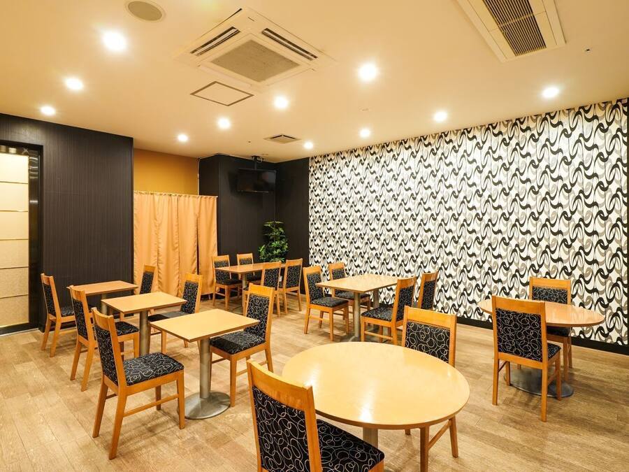 A dining area with multiple tables and chairs, a patterned wall, and a plant.