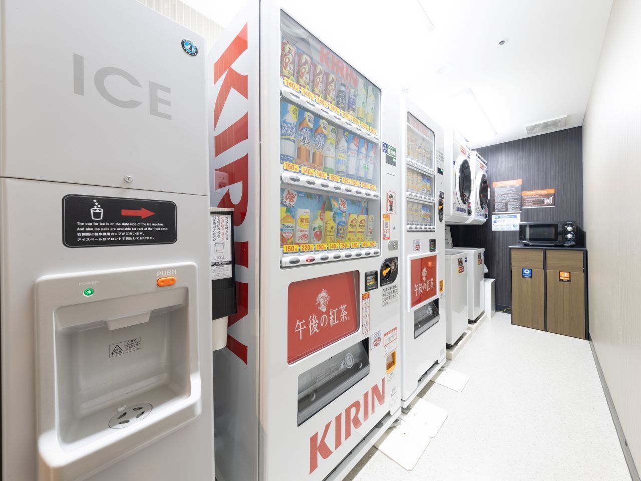 Een rij automaten met ijsdispensers en een magnetron in een gang.