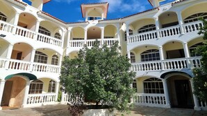 Un edificio a più piani con balconi e archi bianchi, caratterizzato da un cortile centrale con un albero.