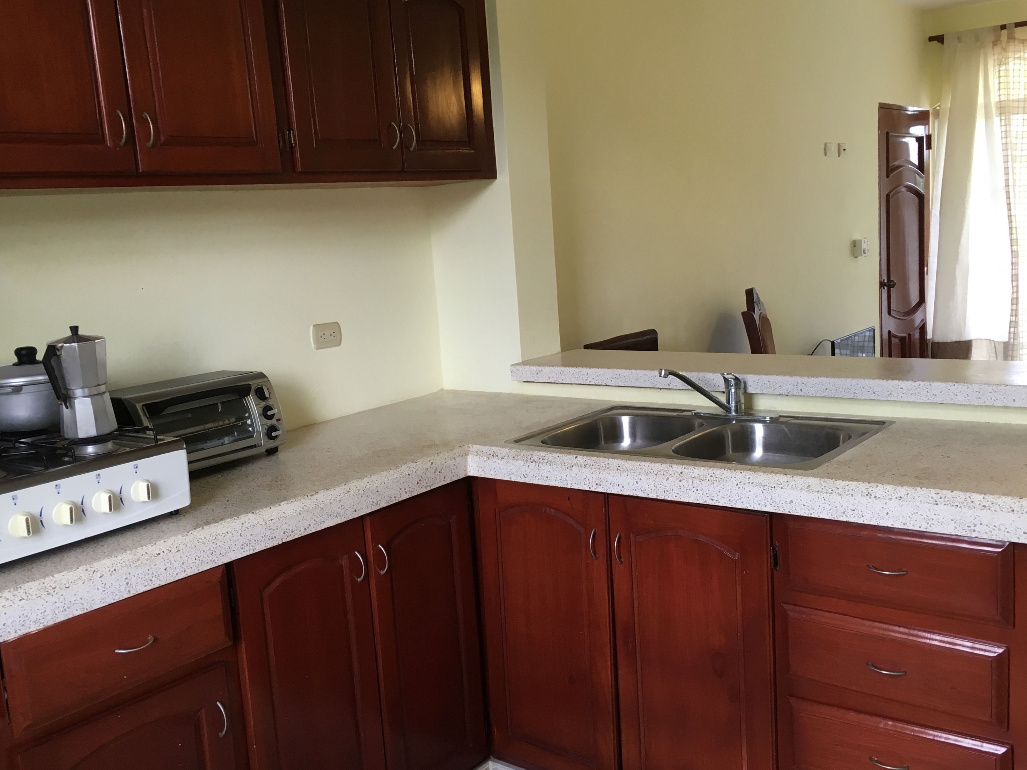 A kitchen with wooden cabinets, a gas stove, a toaster, and a sink.