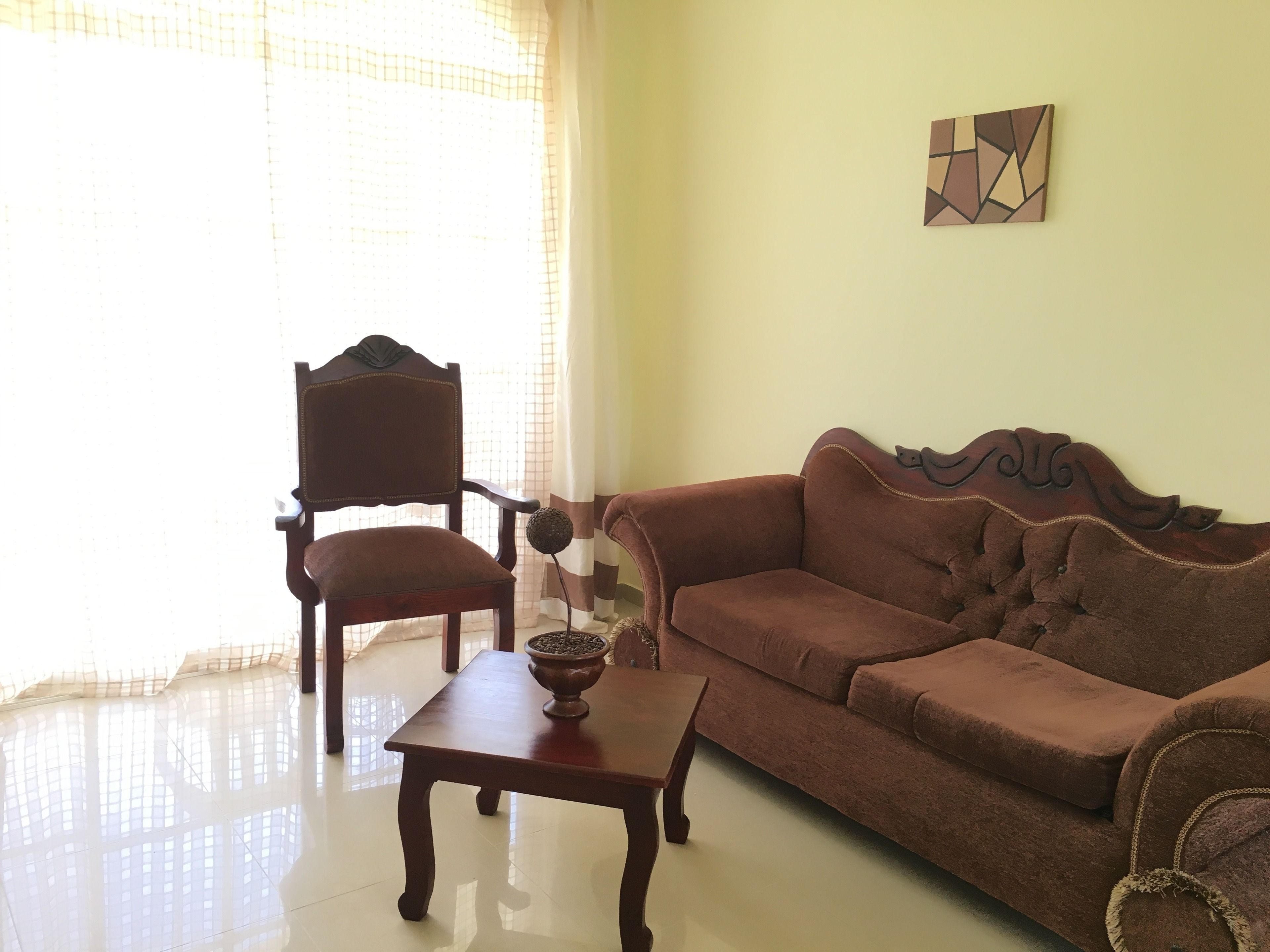 A living room with a wooden chair, a brown sofa, and a small wooden table with a decorative bowl.