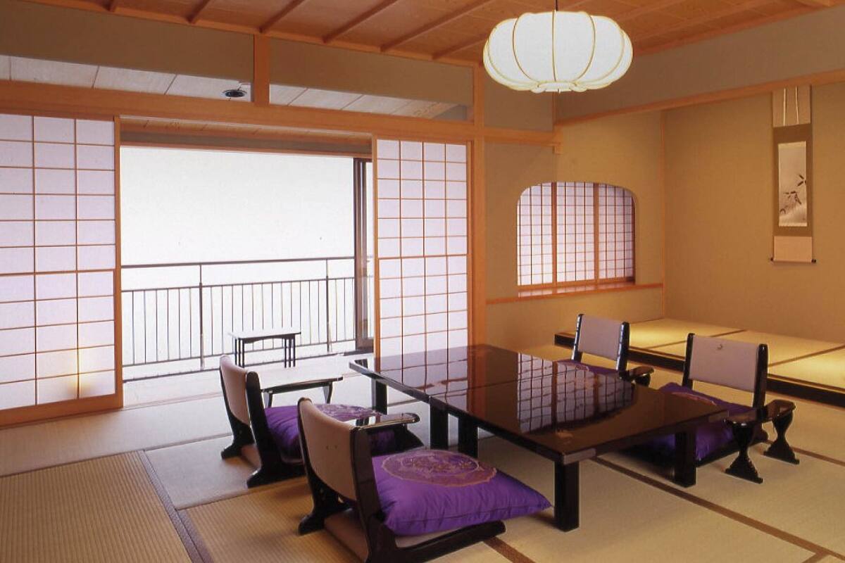 A traditional Japanese room with tatami flooring, a low table, and a cushioned bench.