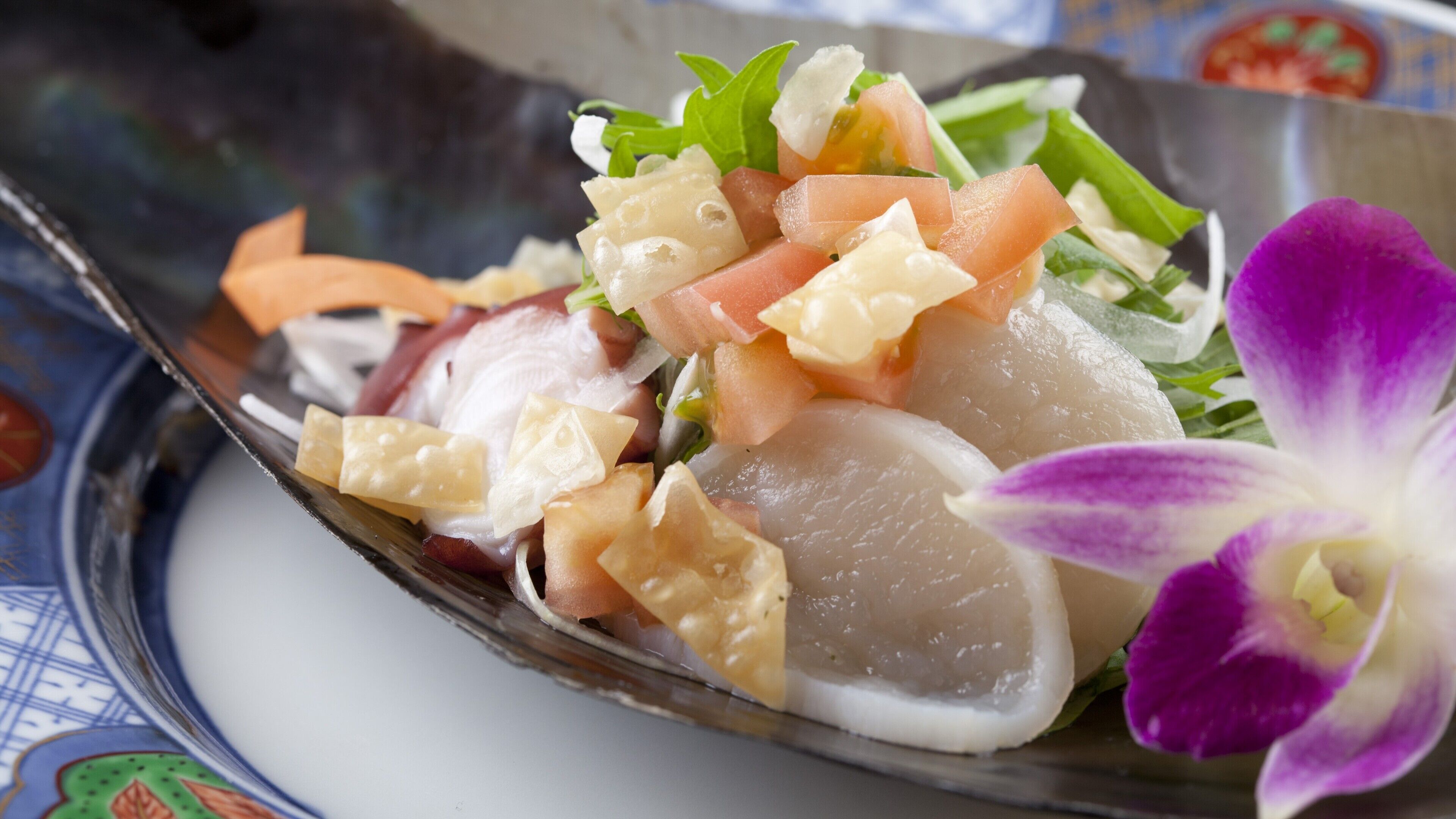 A seafood dish with various toppings and a purple orchid.