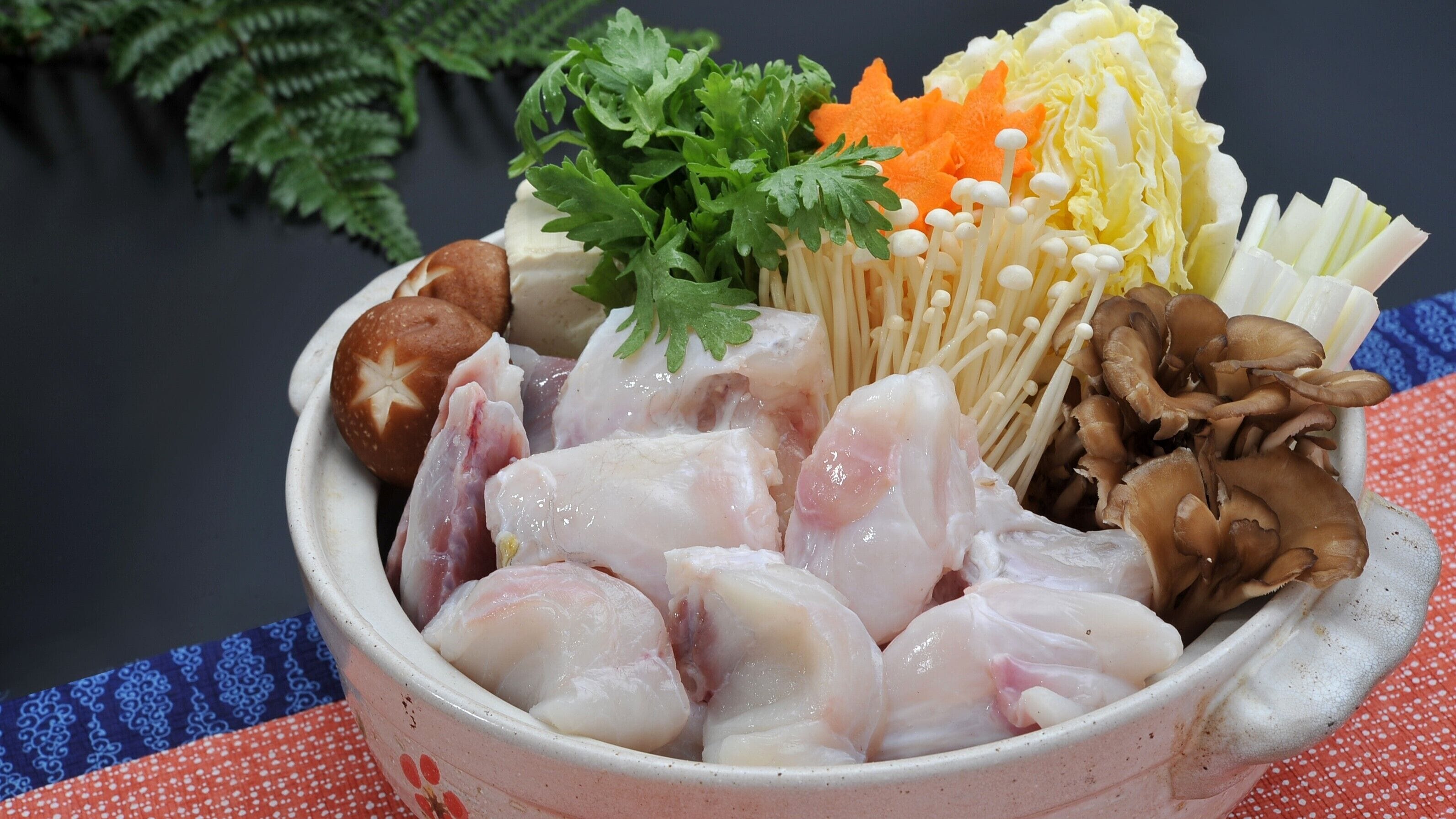 A bowl of raw fish, mushrooms, and vegetables on a table.