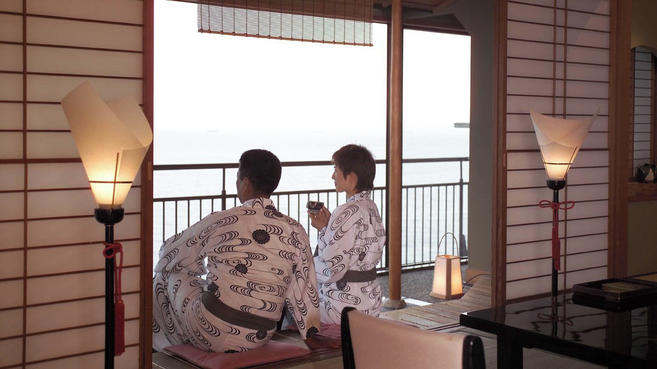 A traditional Japanese room with tatami flooring, shoji screens, and a balcony with a view.
