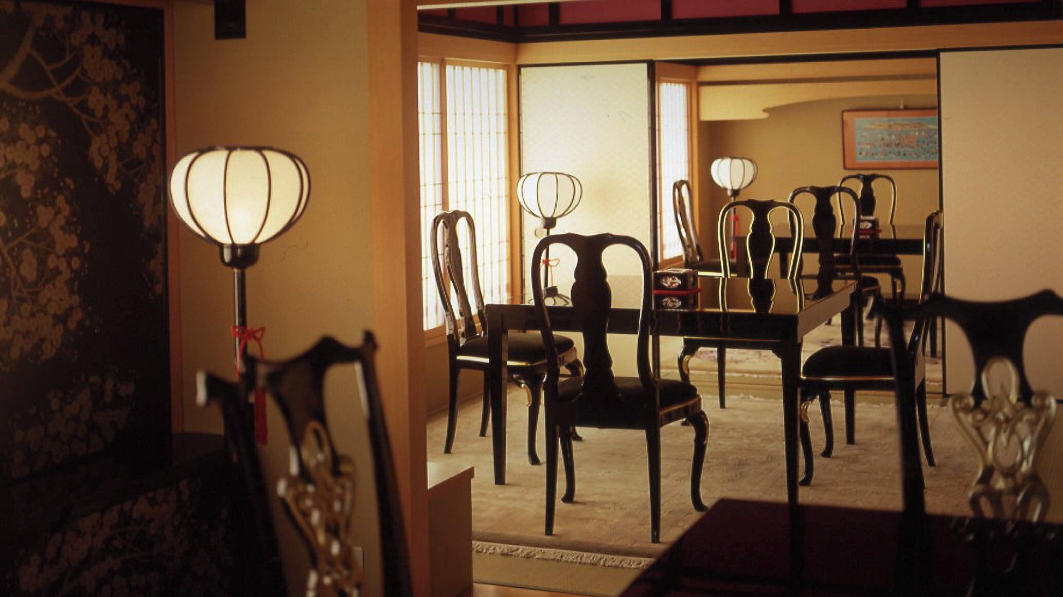 A traditional Japanese-style room with tatami flooring, a low table, and chairs.