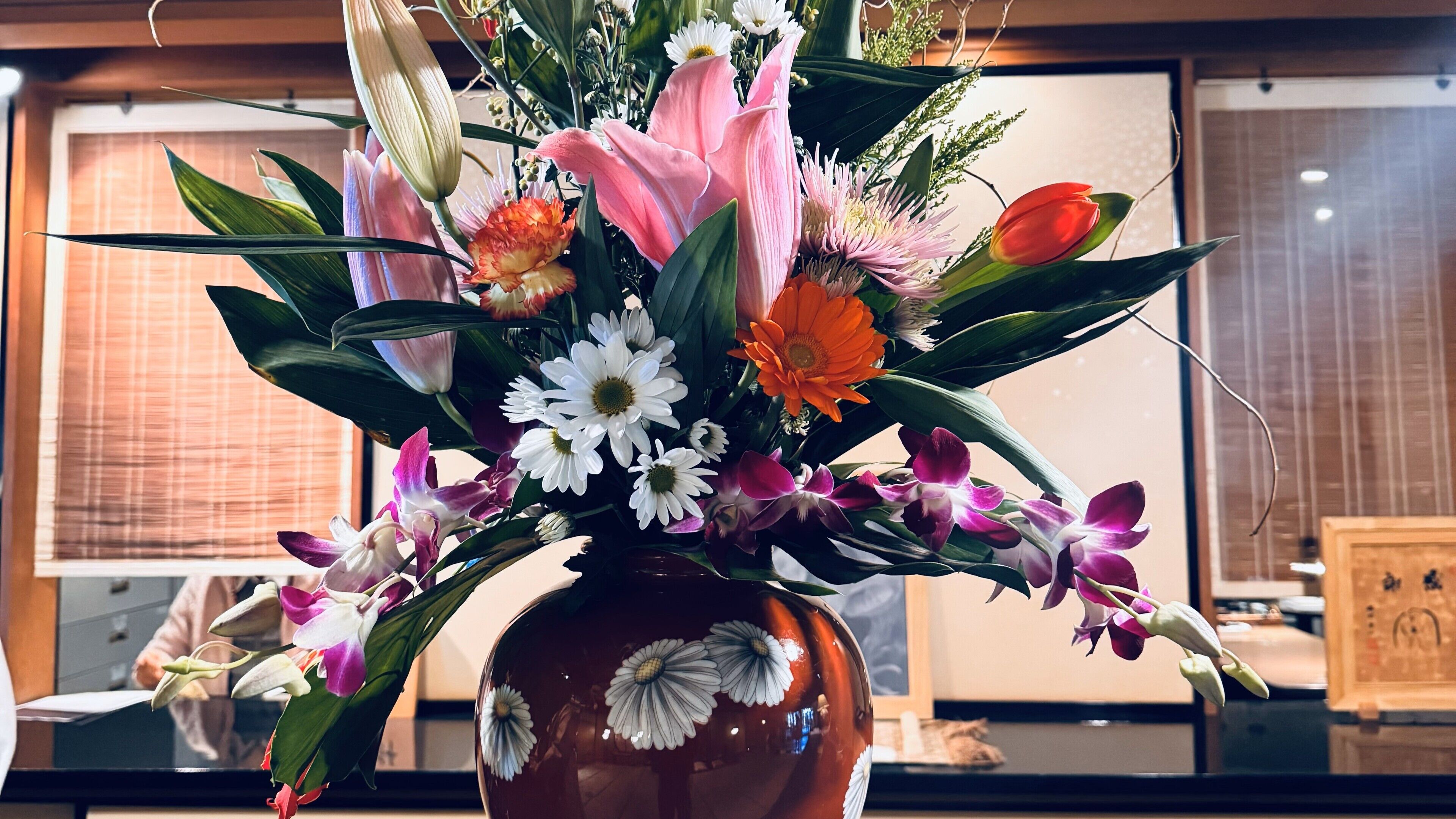 A vase with a floral arrangement including various flowers and leaves.