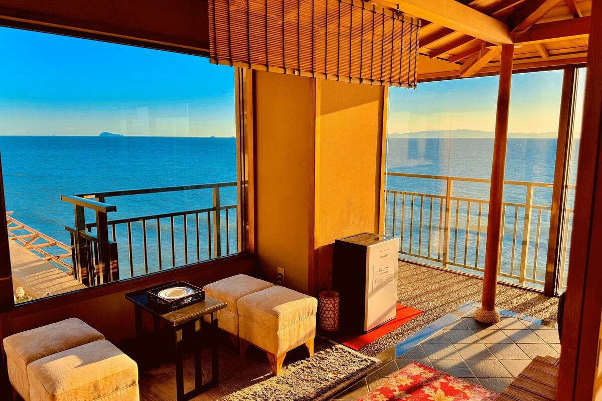 A balcony with a view of the sea, a sofa, a small table, and a speaker.