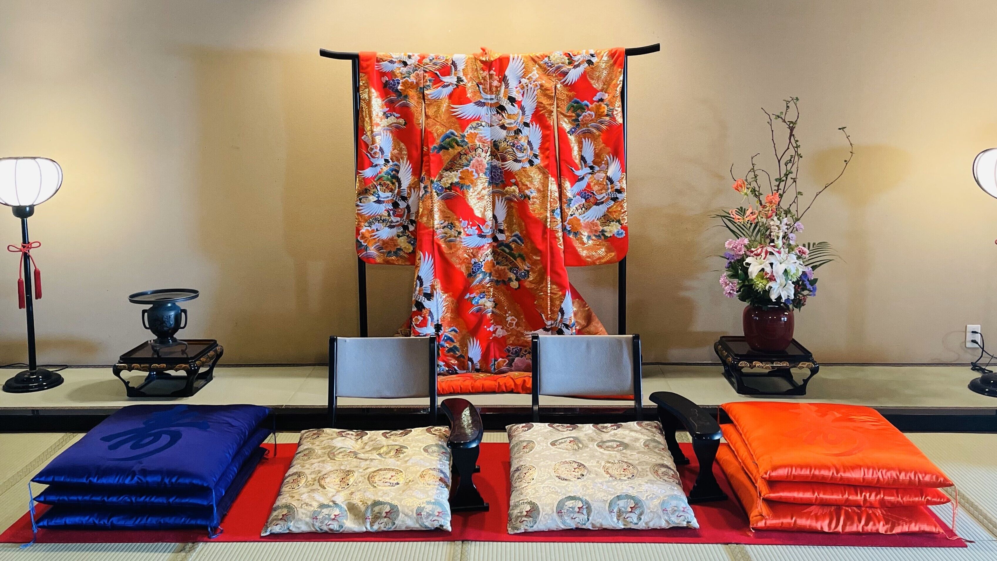 Une pièce de style japonais traditionnel, avec des tatamis, un paravent en papier de riz (shoji), une petite table sur laquelle est disposé un service à thé et un vase rempli de fleurs.