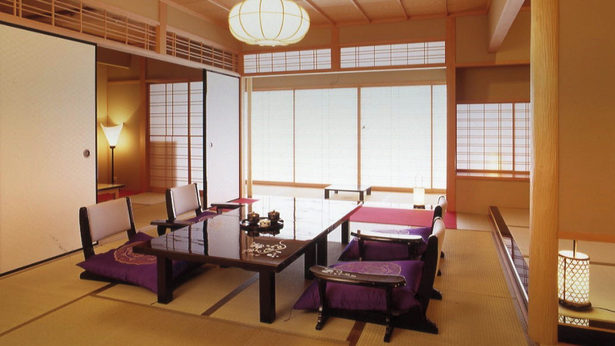A traditional Japanese room with tatami flooring, low tables, and cushions.