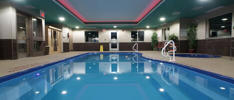 A swimming pool with a blue interior, surrounded by beige walls and a green ceiling with red accents.