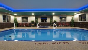 An indoor swimming pool with a 1.4m/4'6" depth, surrounded by red chairs and potted plants. - Dreamz Inn (Central Huron)