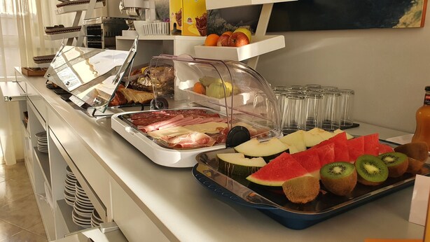 Un bufé con diversas opciones de comida, incluyendo carnes, quesos, frutas y verduras.