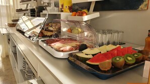 Un bufé con diversas opciones de comida, incluyendo carnes, quesos, frutas y verduras.