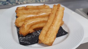 Un plato de churros con azúcar sobre un plato blanco.