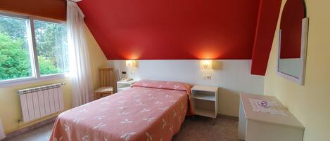 A bedroom with a bed, bedside tables, a chair, a radiator, and a window with curtains.