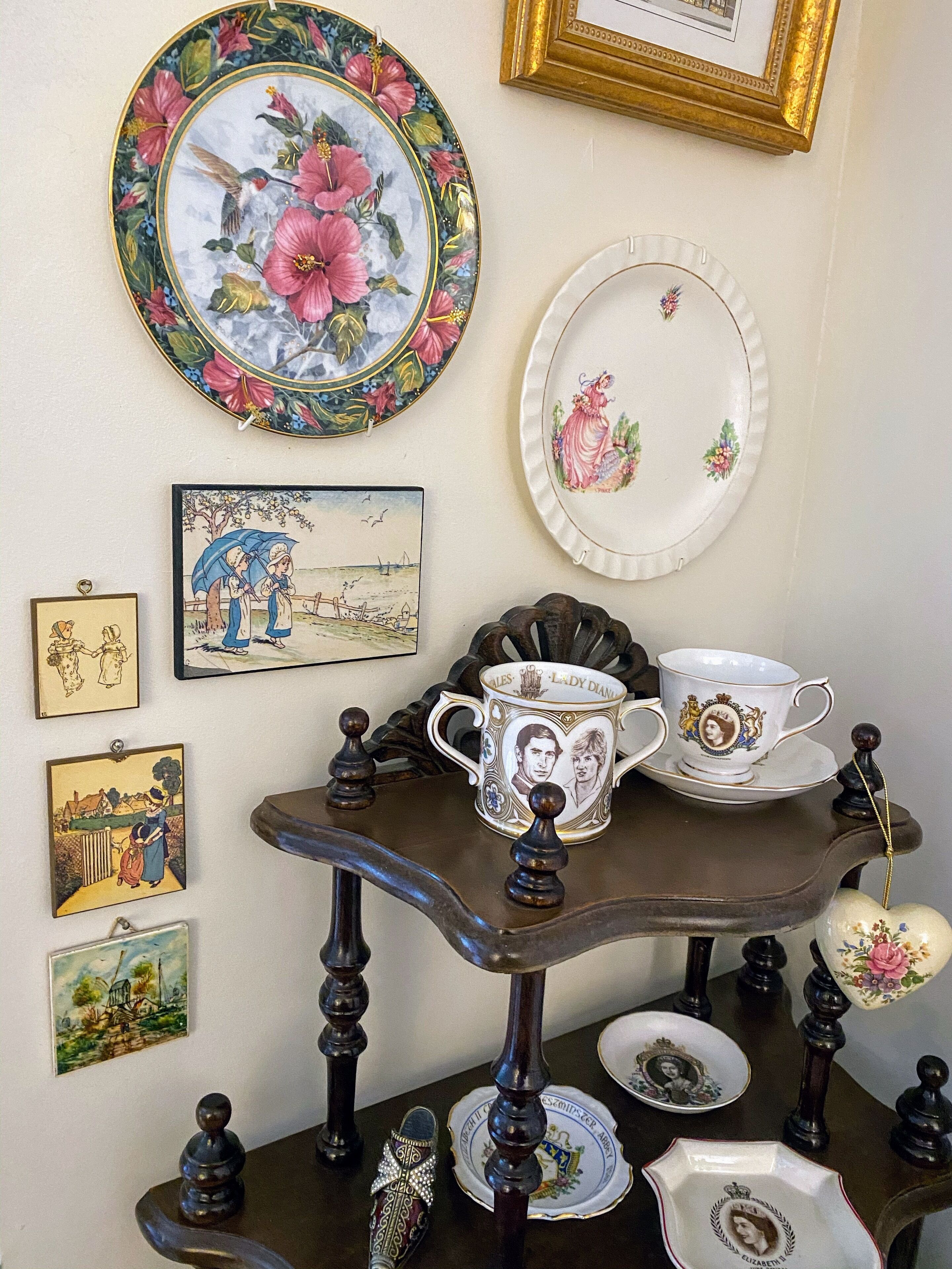 A vintage-style table with ornate plates, a teacup, and a framed picture on the wall.