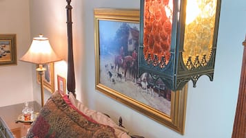 Quarto com cama, abajur, quadro emoldurado e espelho decorativo.