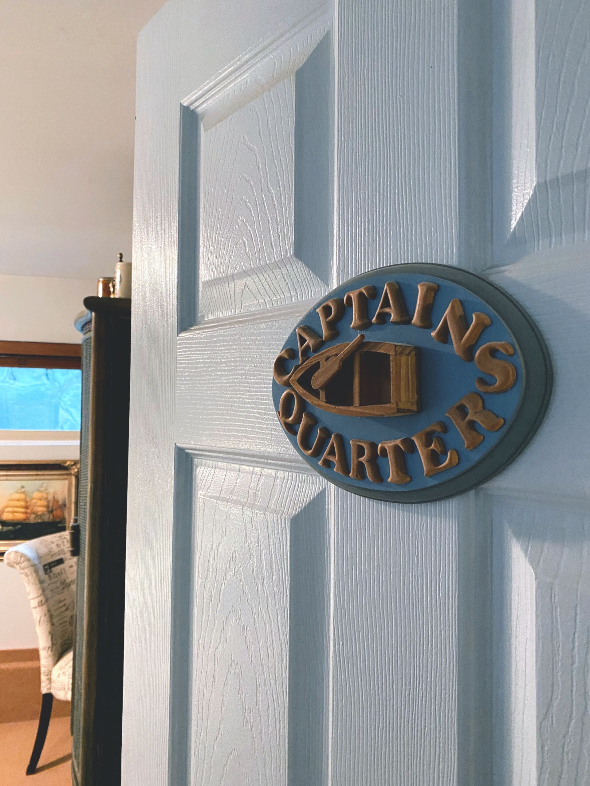 Una puerta con una placa de latón que dice "CAPTAINS QUARTER".