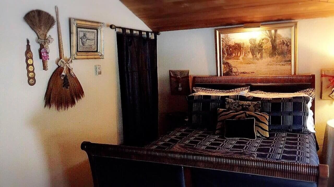 Een kamer met een bed, houten plafond, een schilderij en een hangend klok.