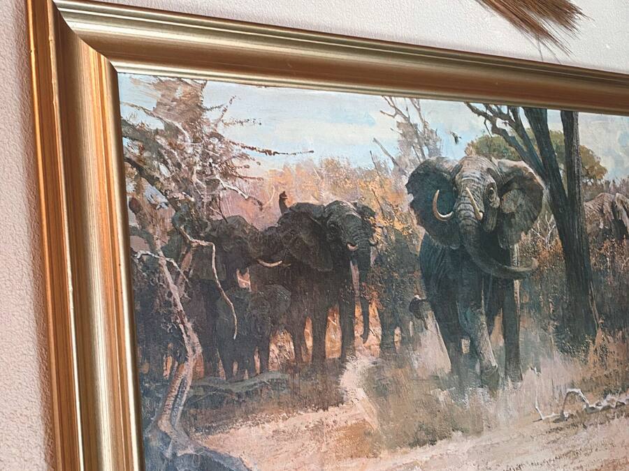 Un tableau encadré représentant des éléphants sur un mur à texture.