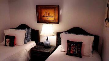A hotel room with two beds, a nightstand with a lamp, and a framed picture on the wall.