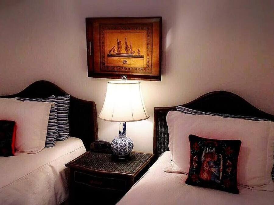 A hotel room with two beds, a nightstand with a lamp, and a framed picture on the wall.