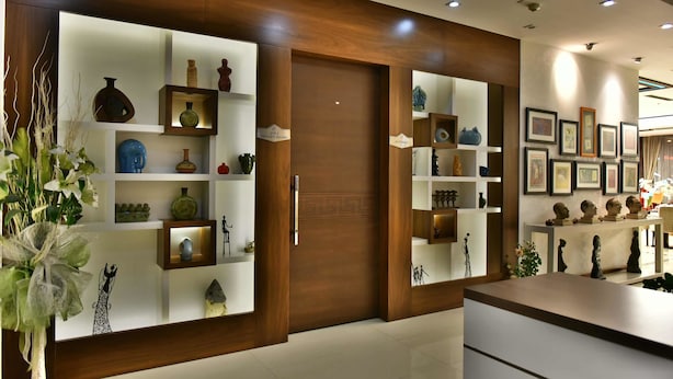 Een modern interieur met houten lambrisering, planken met decoratieve objecten, en een centrale deur met een geometrisch ontwerp.