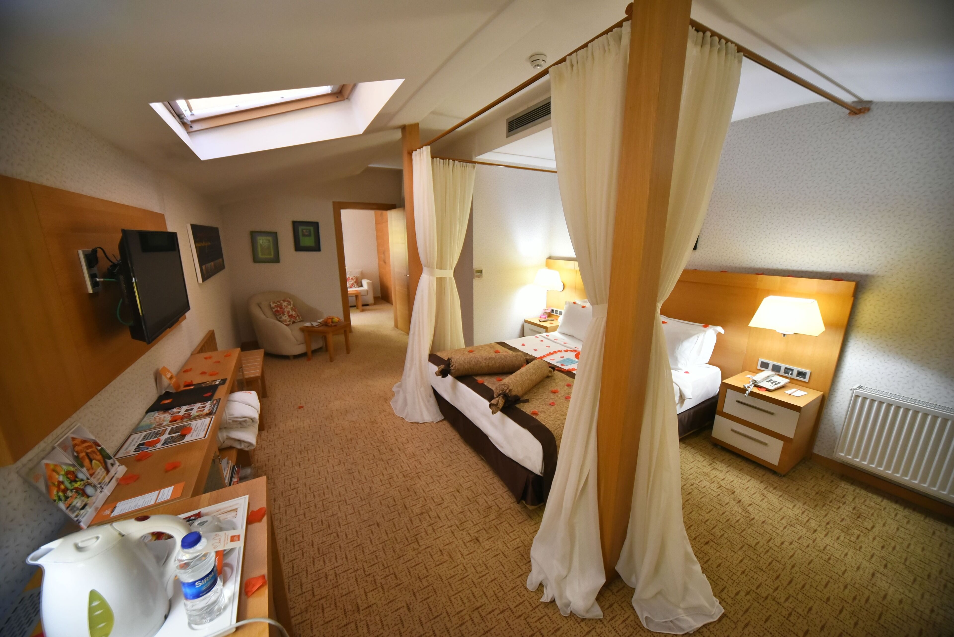 A hotel room with a bed, a desk, a chair, a TV, and a window with curtains.