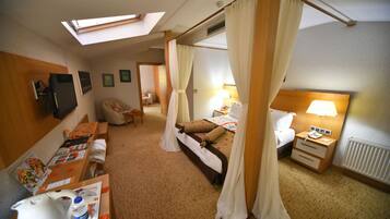 A hotel room with a bed, a desk, a chair, a TV, and a window with curtains.