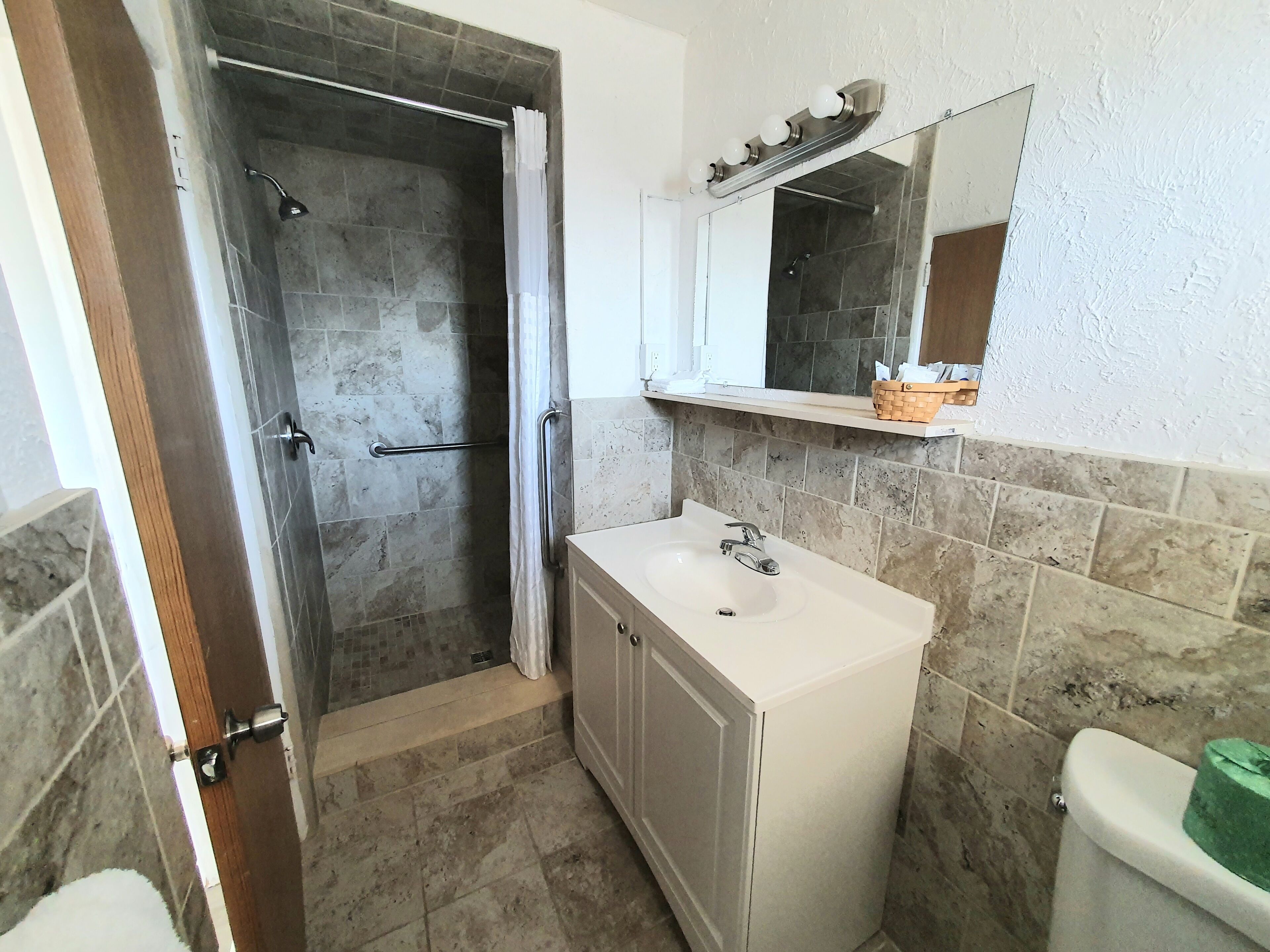 A bathroom with a shower, sink, and toilet.