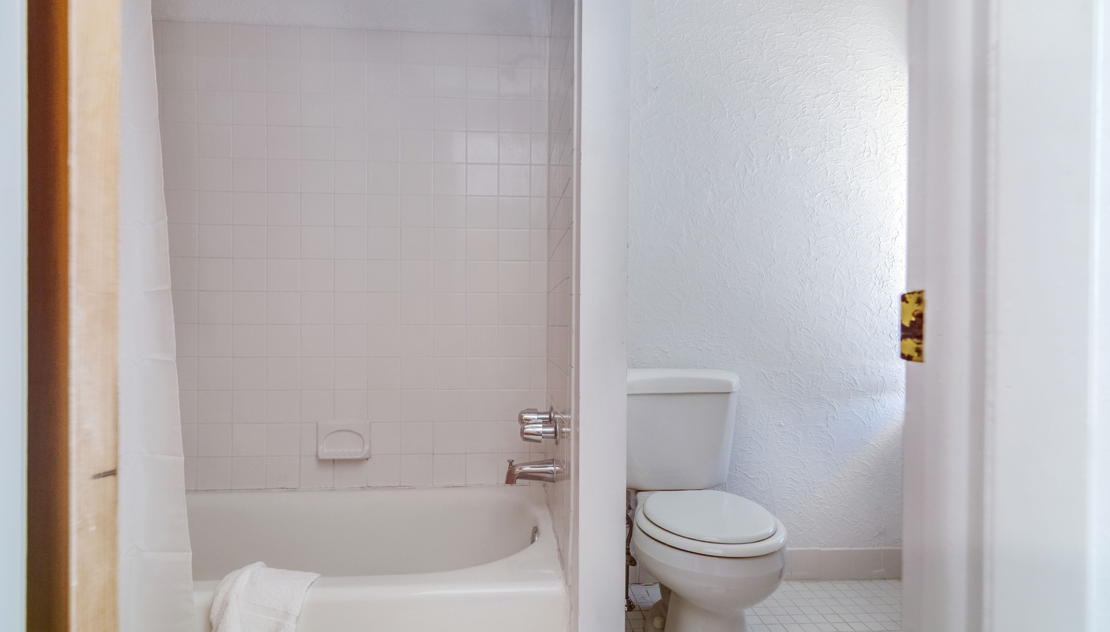 A bathroom with a bathtub, toilet, and tiled walls.