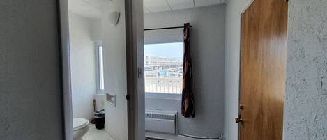 A narrow hallway with a view of a bathroom and a balcony.