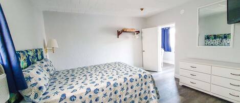 Un dormitorio con cama, cómoda, espejo y puerta que da a otra habitación.