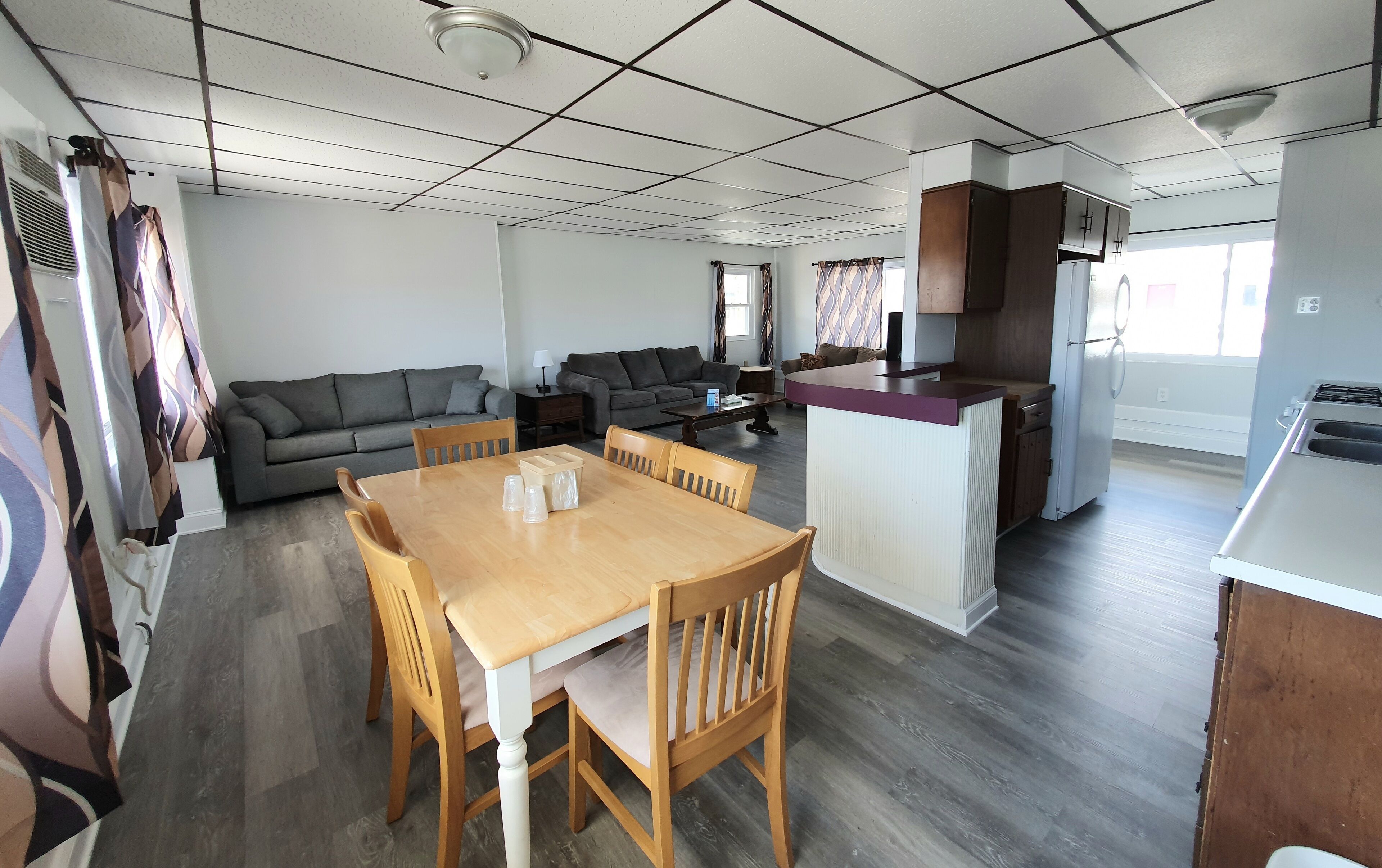 A modern living room with a dining area, a kitchen, and a large window.