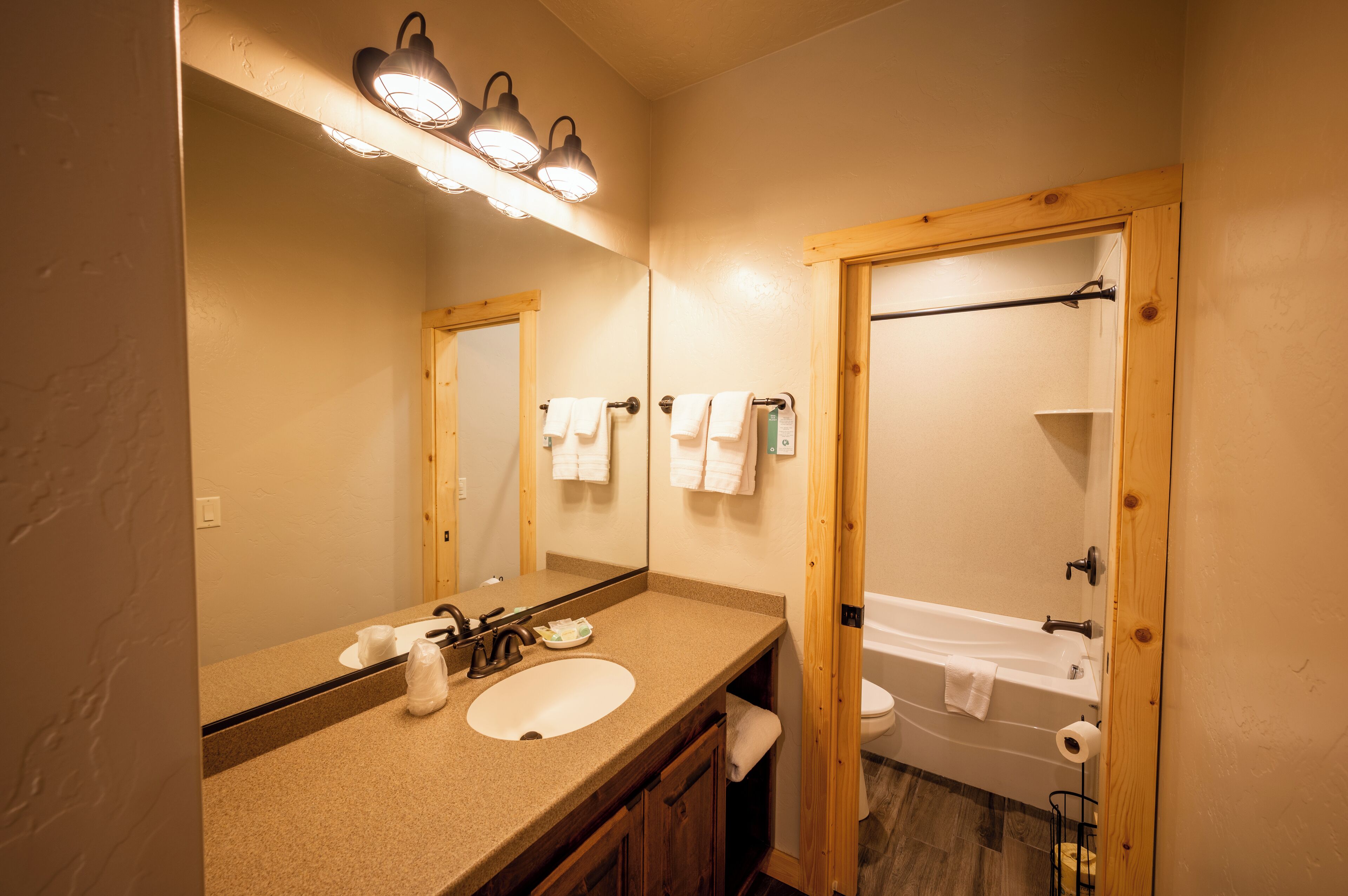 Une salle de bain avec un lavabo, un miroir et une porte en bois donnant accès à une baignoire.