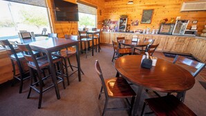 A wooden interior with tables and chairs, a counter with a display case, and a television mounted on the wall. - Bryce Canyon Inn (Tropic)