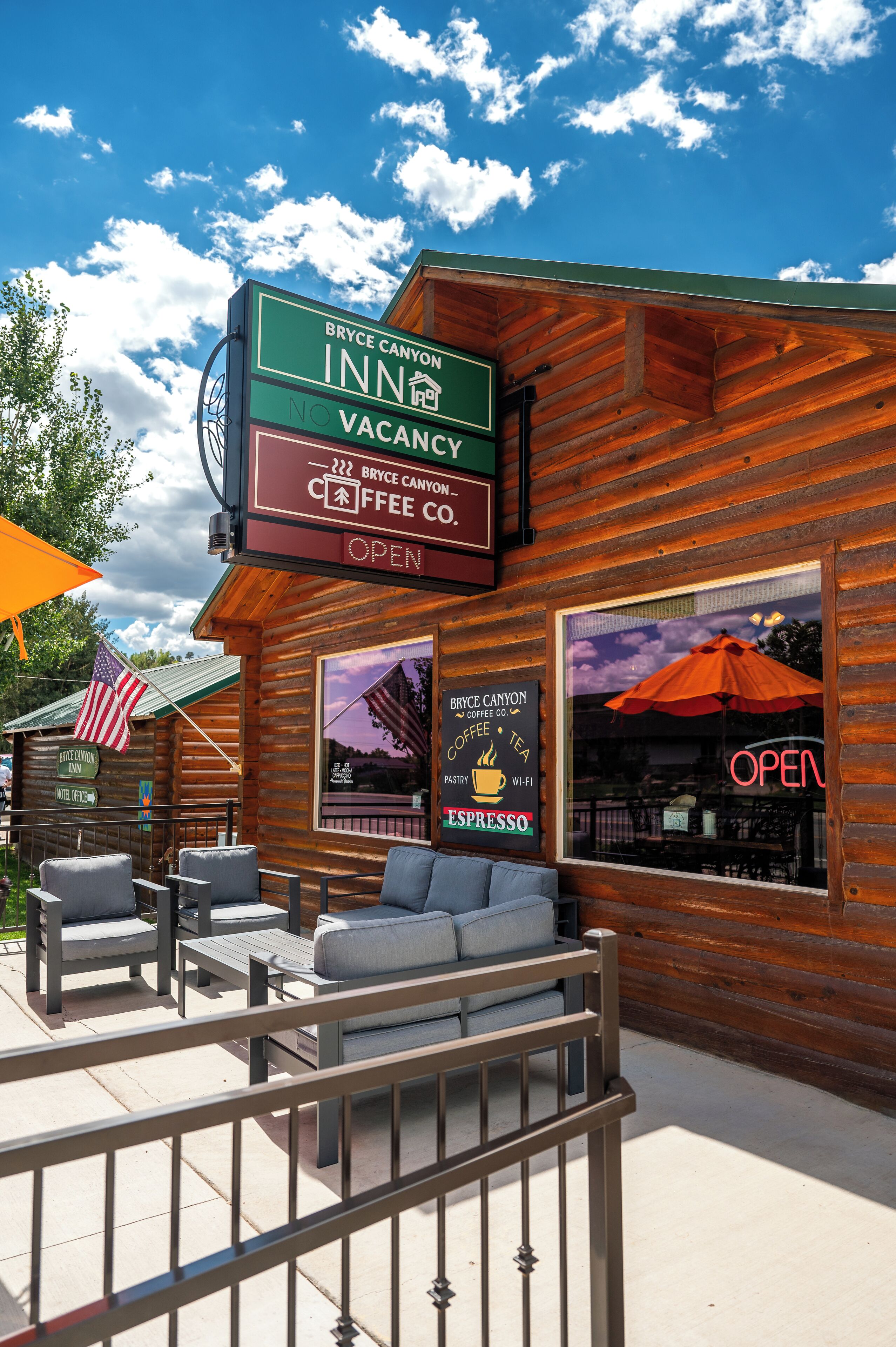 Un établissement d’hébergement de style chalet en bois, doté d’une terrasse, d’une pancarte indiquant qu’il n’y a plus de chambres disponibles et d’une enseigne de café.
