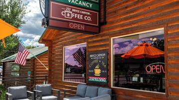 Un établissement d’hébergement de style chalet en bois, doté d’une terrasse, d’une pancarte indiquant qu’il n’y a plus de chambres disponibles et d’une enseigne de café.