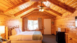 A log cabin bedroom with a large bed, a smaller bed, a desk, and a ceiling fan. - Bryce Canyon Inn (Tropic)