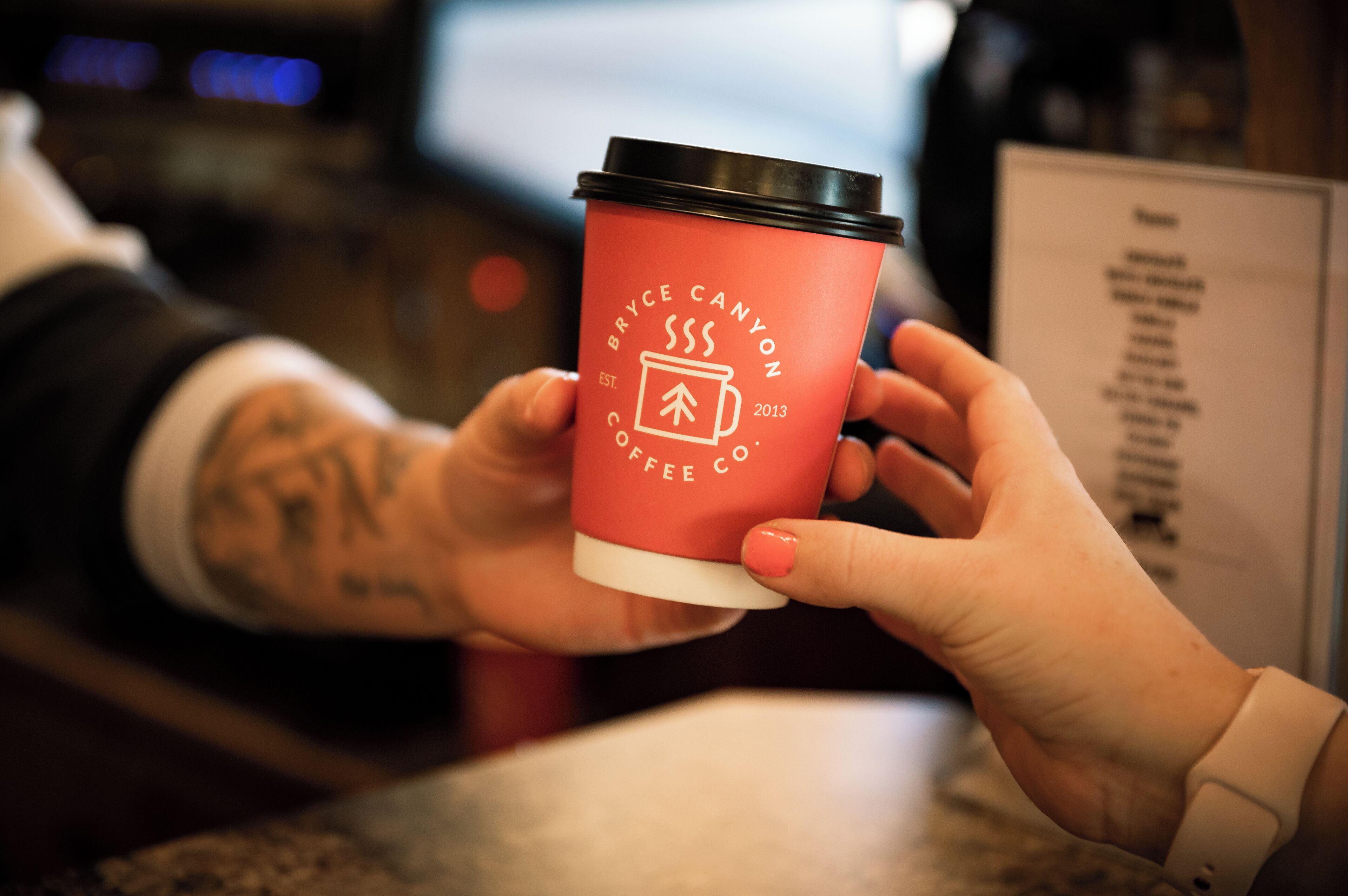 A person holding a red coffee cup with the logo "Bryce Canyon Coffee Co."