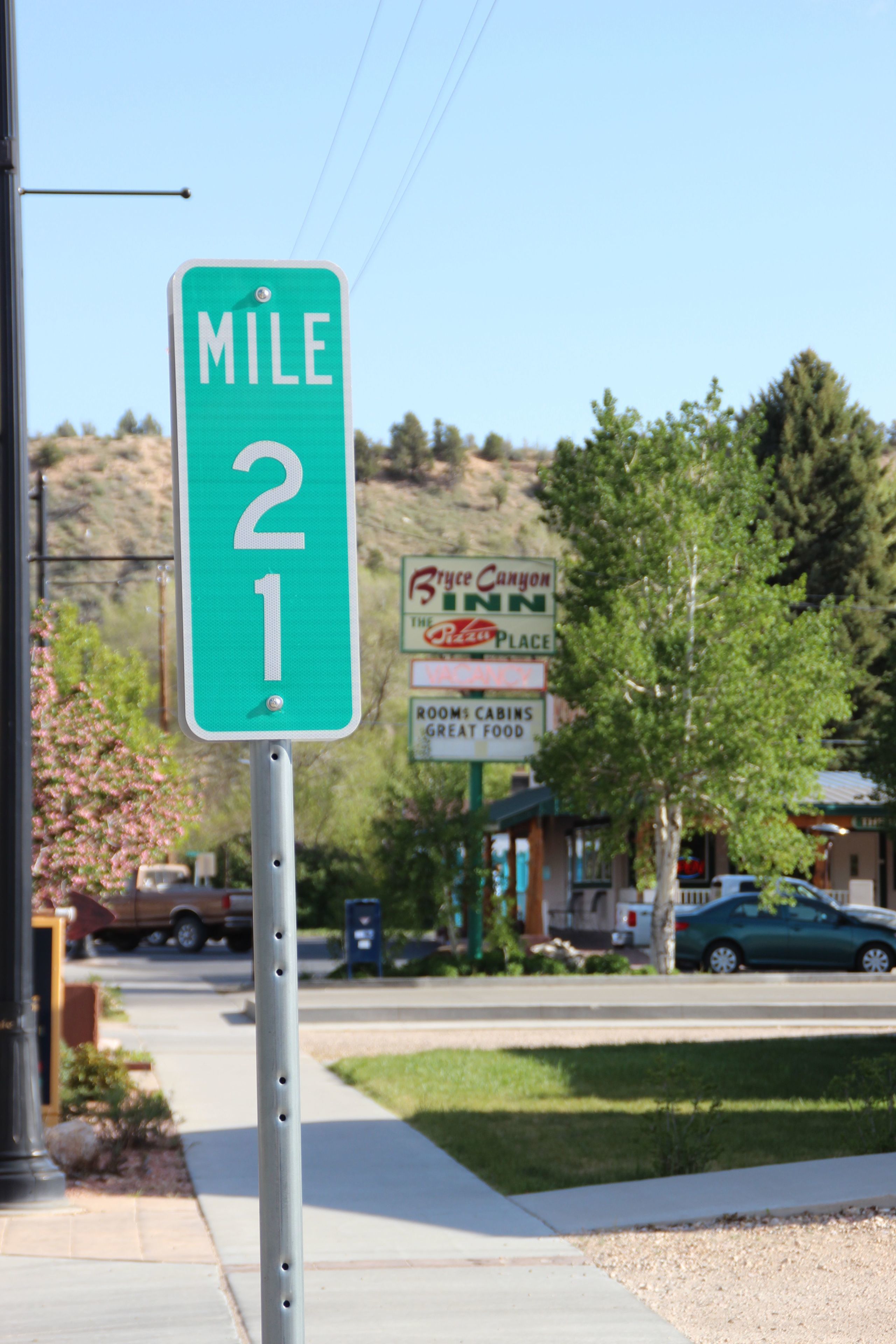 A green mile marker sign with a B&B Canyon Inn sign in the background.