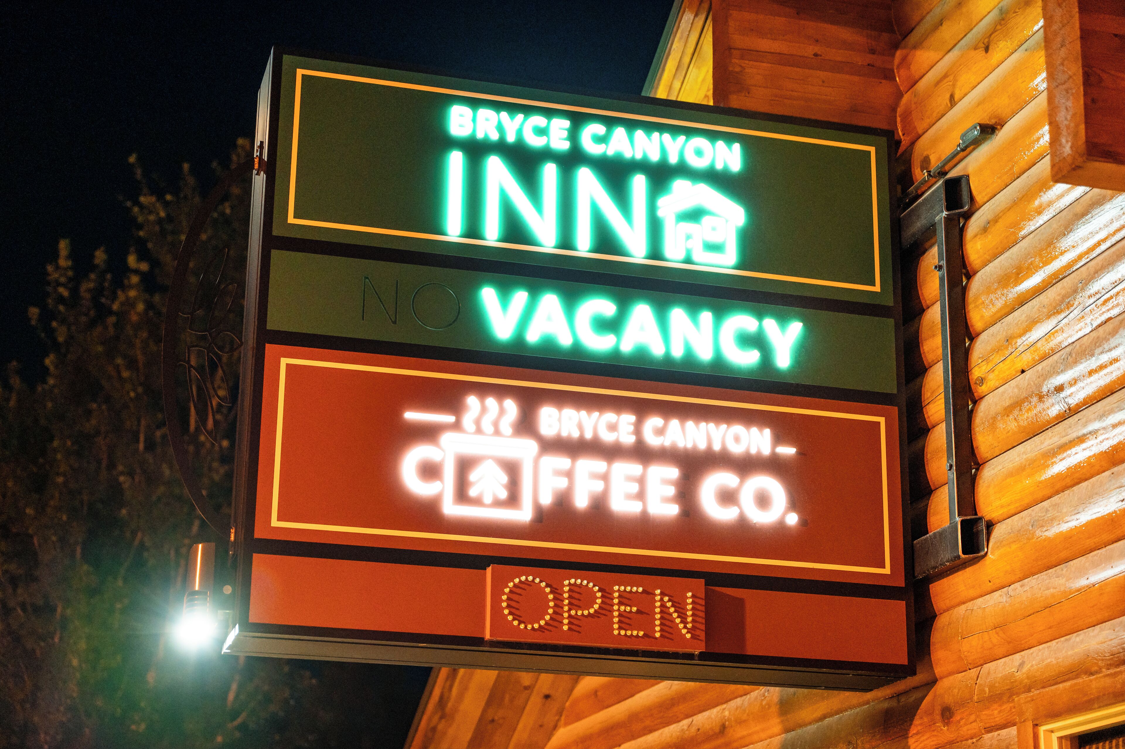 A neon sign for Bryce Canyon Inn with a vacancy notice and an open coffee shop.