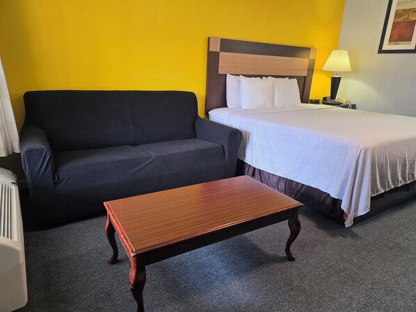 Una camera d'albergo con un letto, un divano e un tavolo in legno.