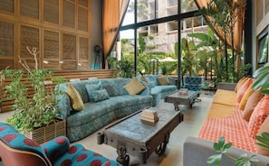 Un espace intĂ©rieur vaste et lumineux, comprenant un grand canapĂ© dâangle, une table basse et un canapĂ© Ă motifs.